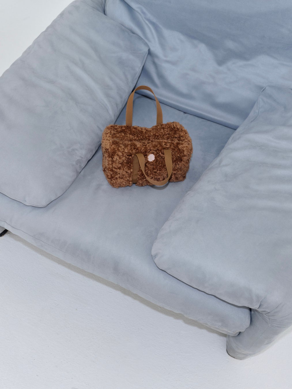 淡いブルーのソファに置かれたminitmuteのshearing tote。ソファは撮影小物