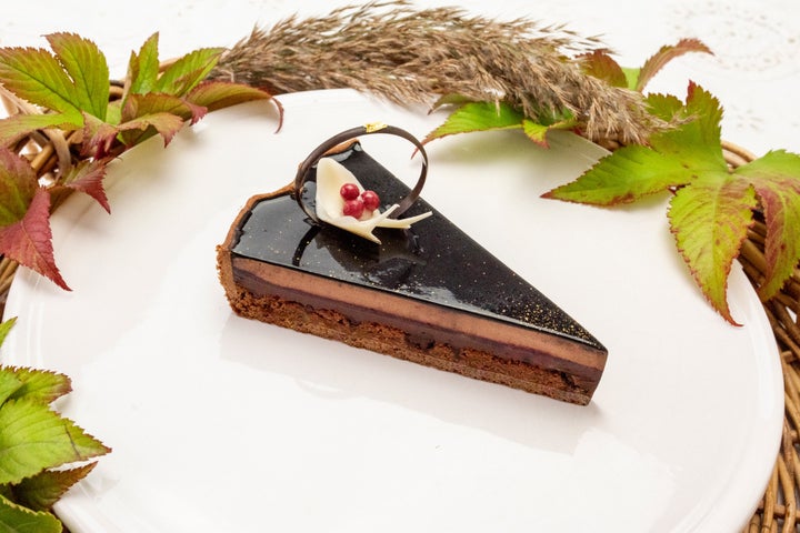 白い皿に置かれた、黒いグラサージュとチョコレートの飾りをのせた「千雅」の1ピース